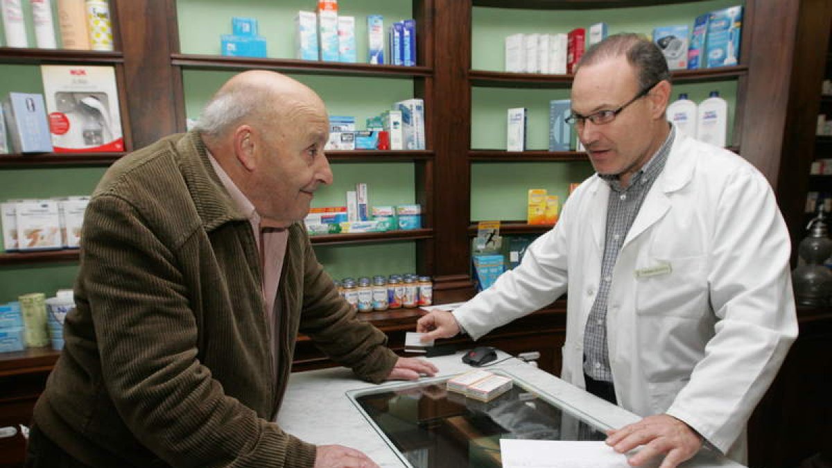 El farmacéutico Andrés Pérez explica a uno de sus usuarios el funcionamiento de la e-receta