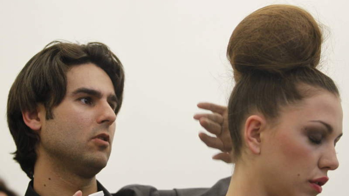 El estilista Óscar March da los últimos toques al peinado de una modelo.