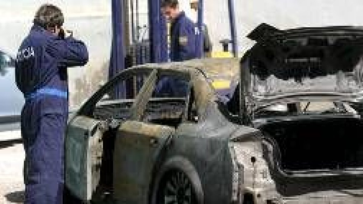 Un policía hace fotos del coche, que quedó totalmente calcinado