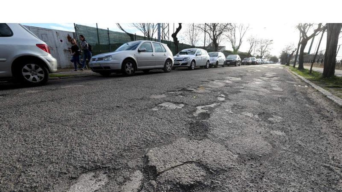 La principal calle que atraviesa el barrio, con cientos de coches a diario, se encuentra en el estado que muestra la imagen. ANA F. BARREDO