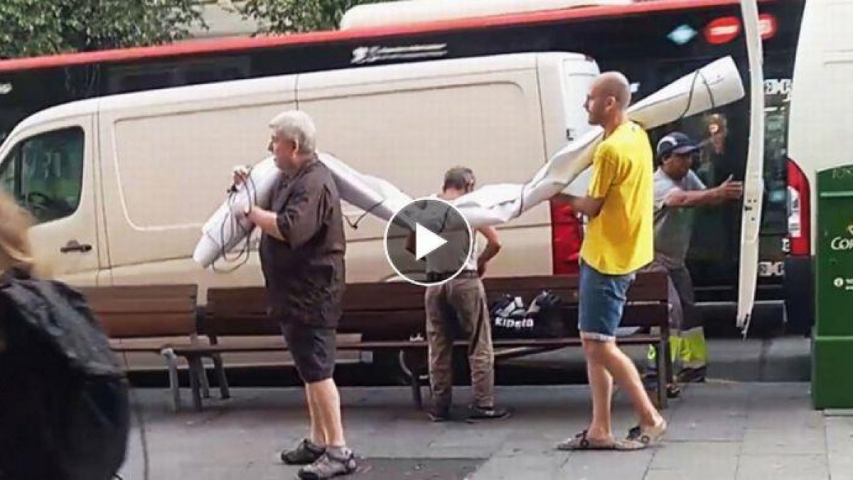 Unos hombres sacan de una furgoneta la pancarta supuestamente contraria al Rey.