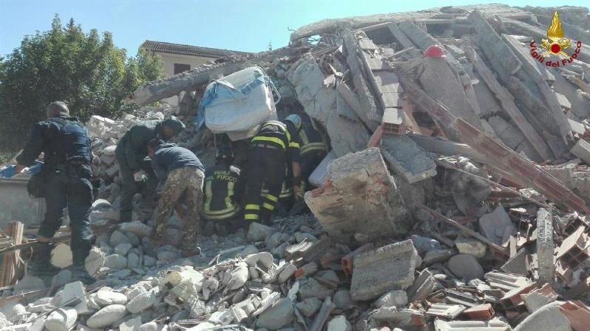 Imagen facilitada por la Brigada de Bomberos de Italia de varios bomberos mientras buscan víctima entre los escombros de un edificio derrumbado en Amatrice, en el centro de Italia, hoy.