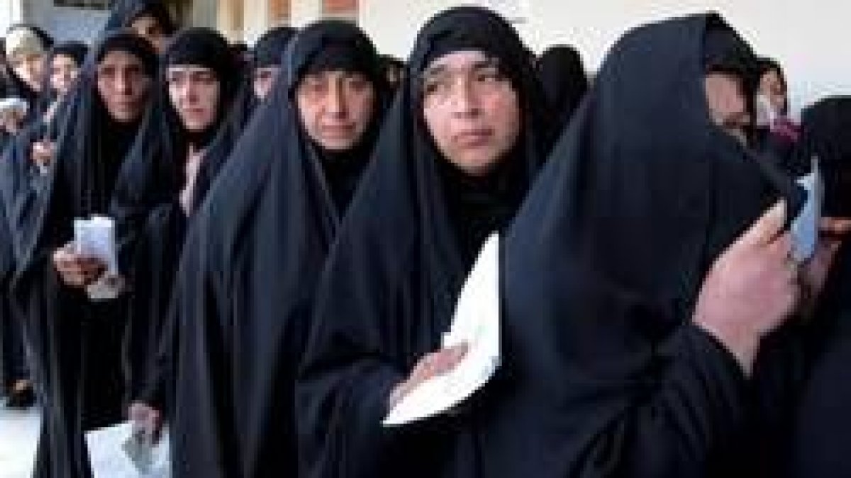 Hombres y mujeres guardan cola por separado para votar en un colegio electoral de Bagdad