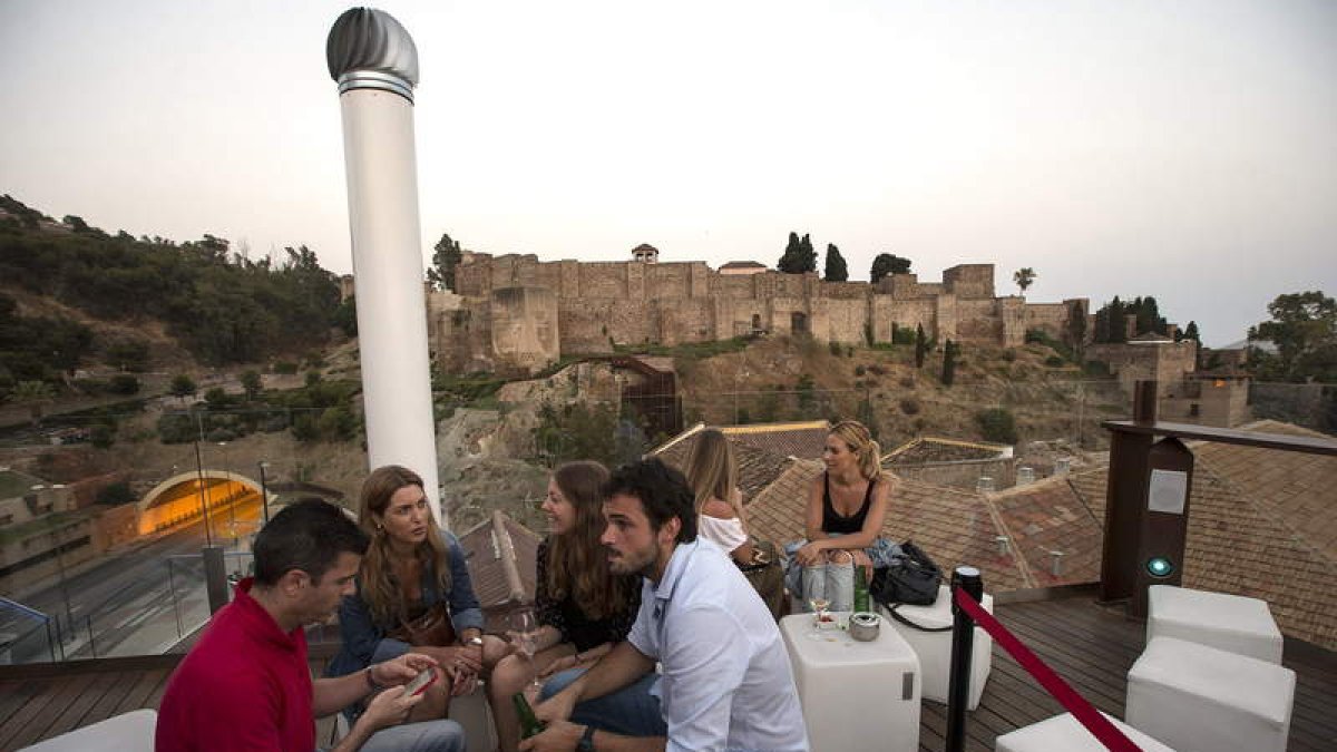 Un grupo de personas en la terraza del Alcazaba Premium Hostel con vistas a este monumento malagueño.