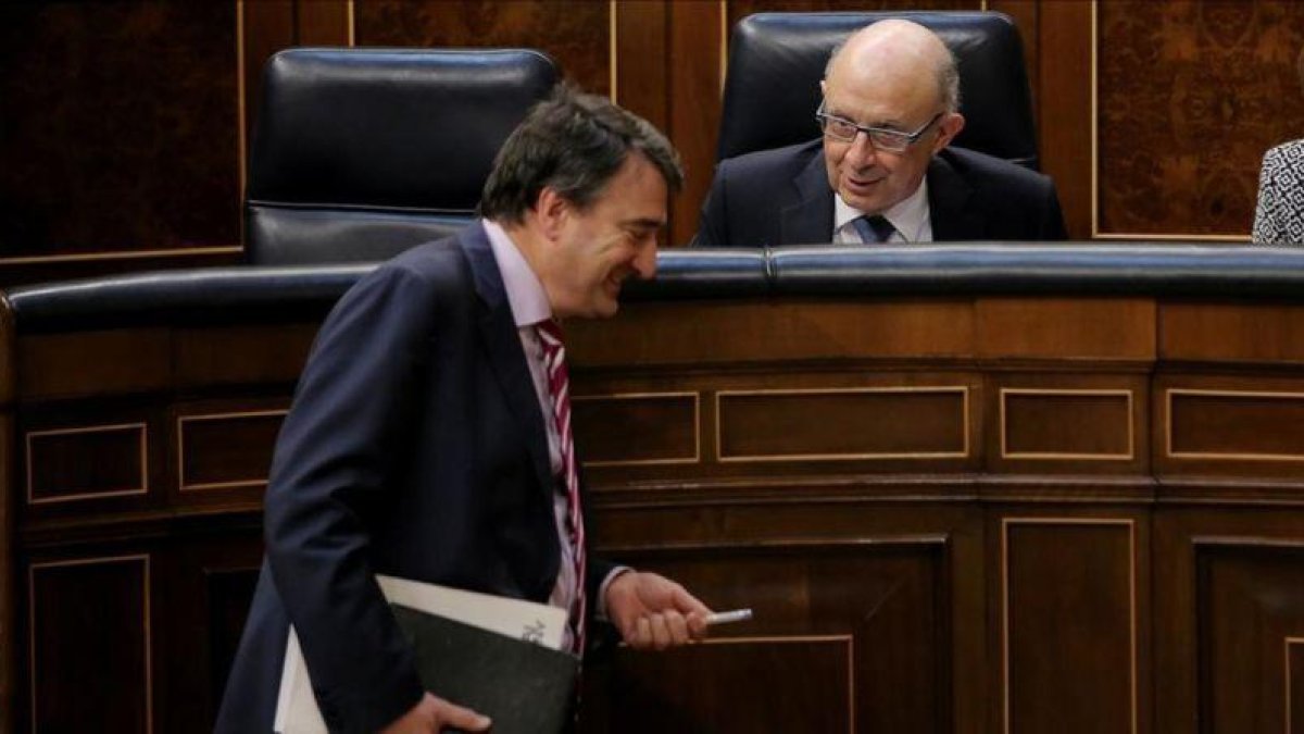 El portavoz del PNV, Aitor Esteban, bromea con el ministro de Hacienda, Cristóbal Montoro, este miércoles en el Congreso