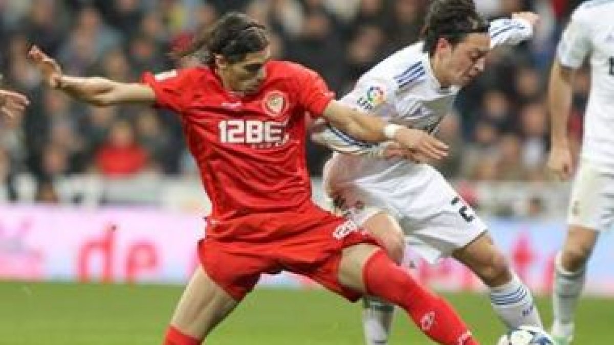 El centrocampista alemán del Madrid, Mesut Özil, luchando con Cáceres.