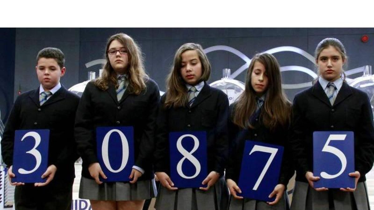 Los niños del Colegio San Ildefonso de Madrid posan con el número ganador del primer premio del sorteo del Niño.