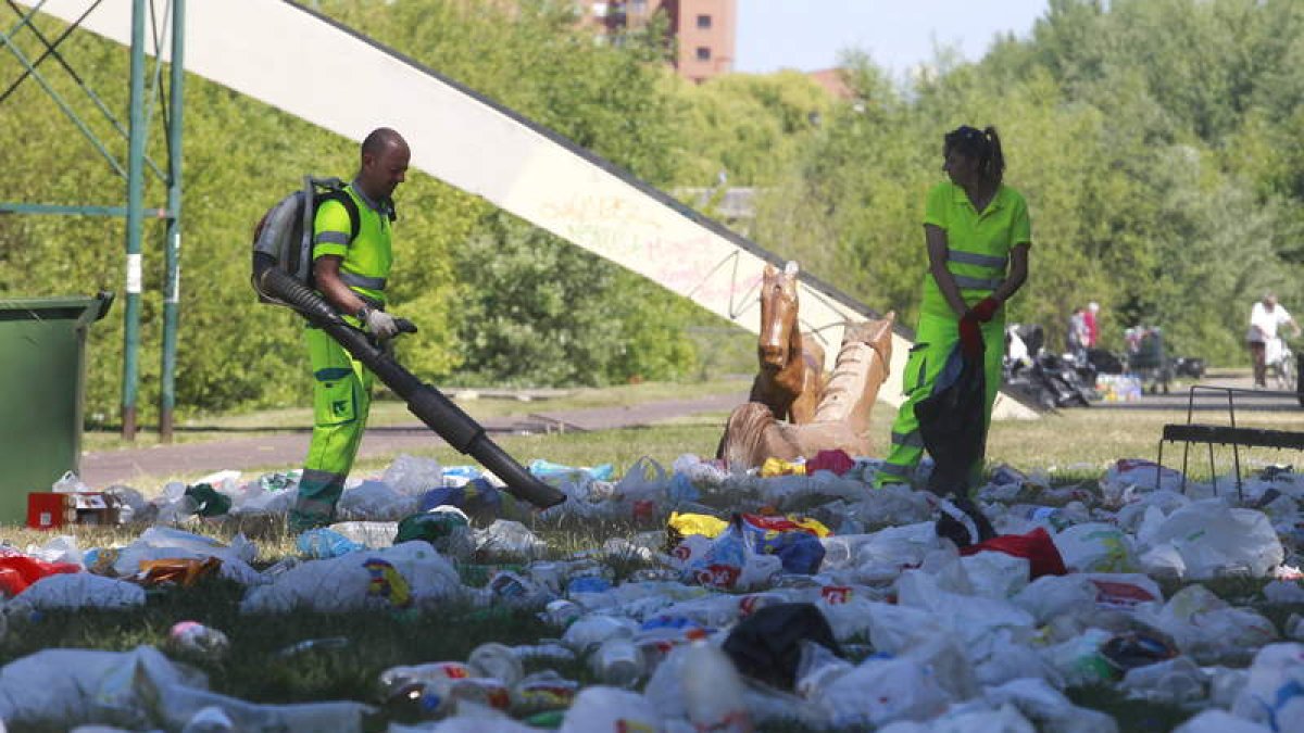 Operarios de jardines limpian de basura las márgenes del río Bernesga.