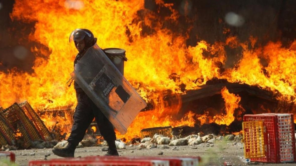 Un policía pasa frente a un camión en llamas durante las protestas contra la reforma educativa en Oaxaca.