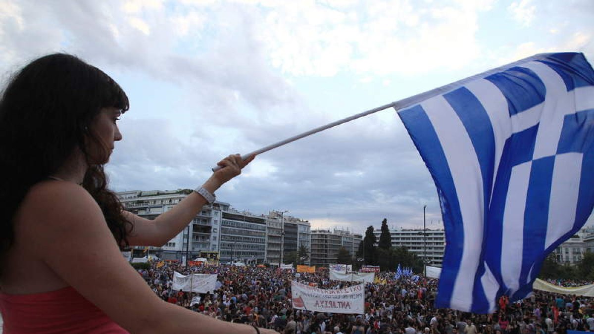 Una mujer ondea una bandera griega en una protesta.