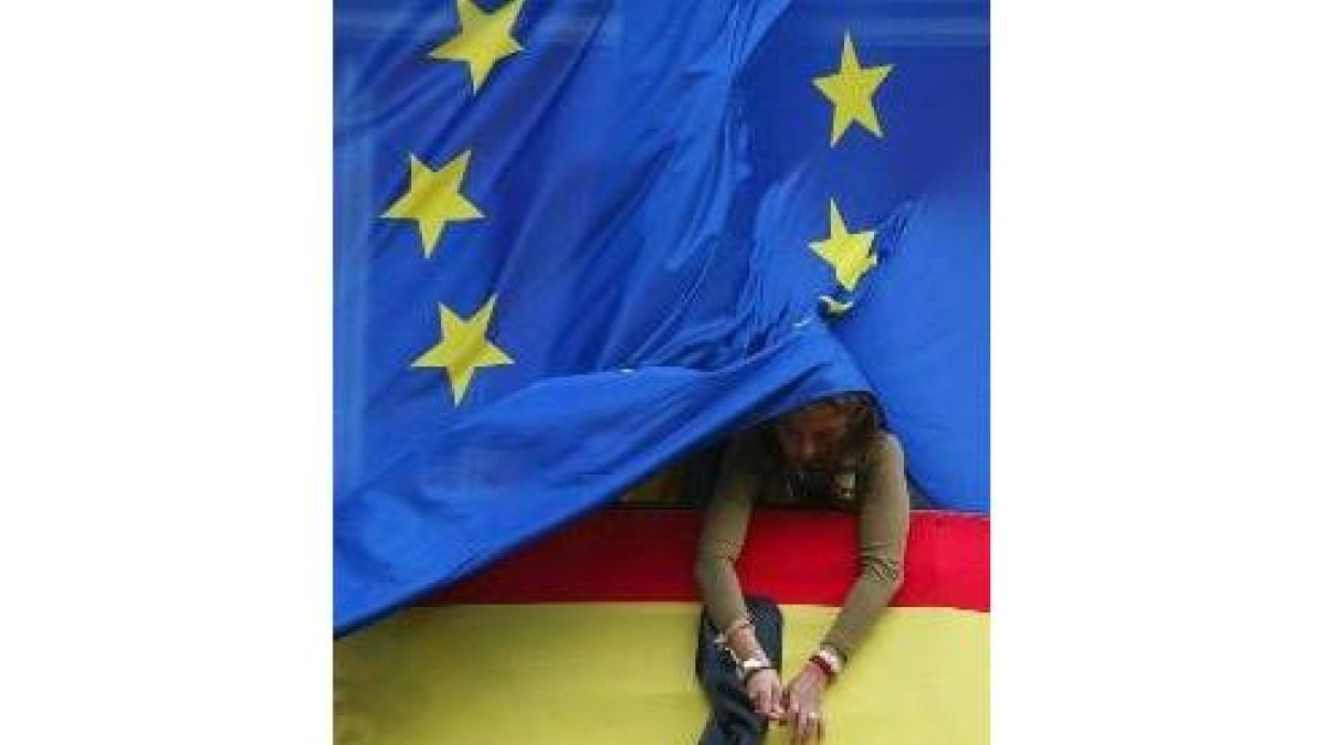 Una funcionaria de la Comunidad de Madrid coloca un crespón negro a una bandera española