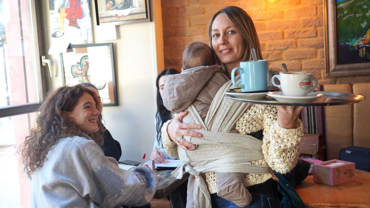 Nuria Salas recurre improvisadamente al porteo para atender una mesa de su negocio hostelero, la cafetería Bellas Artes. J. NOTARIO