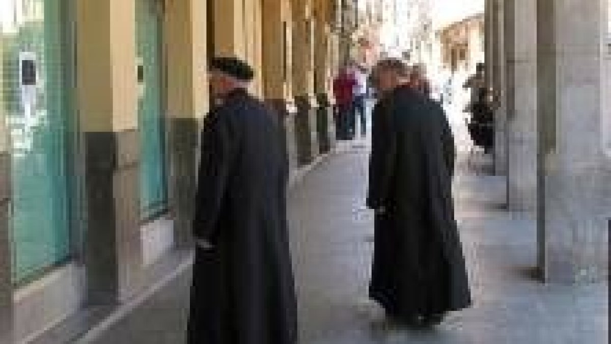 Dos sacerdotes pasean bajo los soportales de la plaza Mayor de Astorga