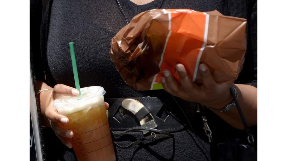 Una mujer pasea por la calle con comida y una bebida de refresco gigante. JUSTIN LANE