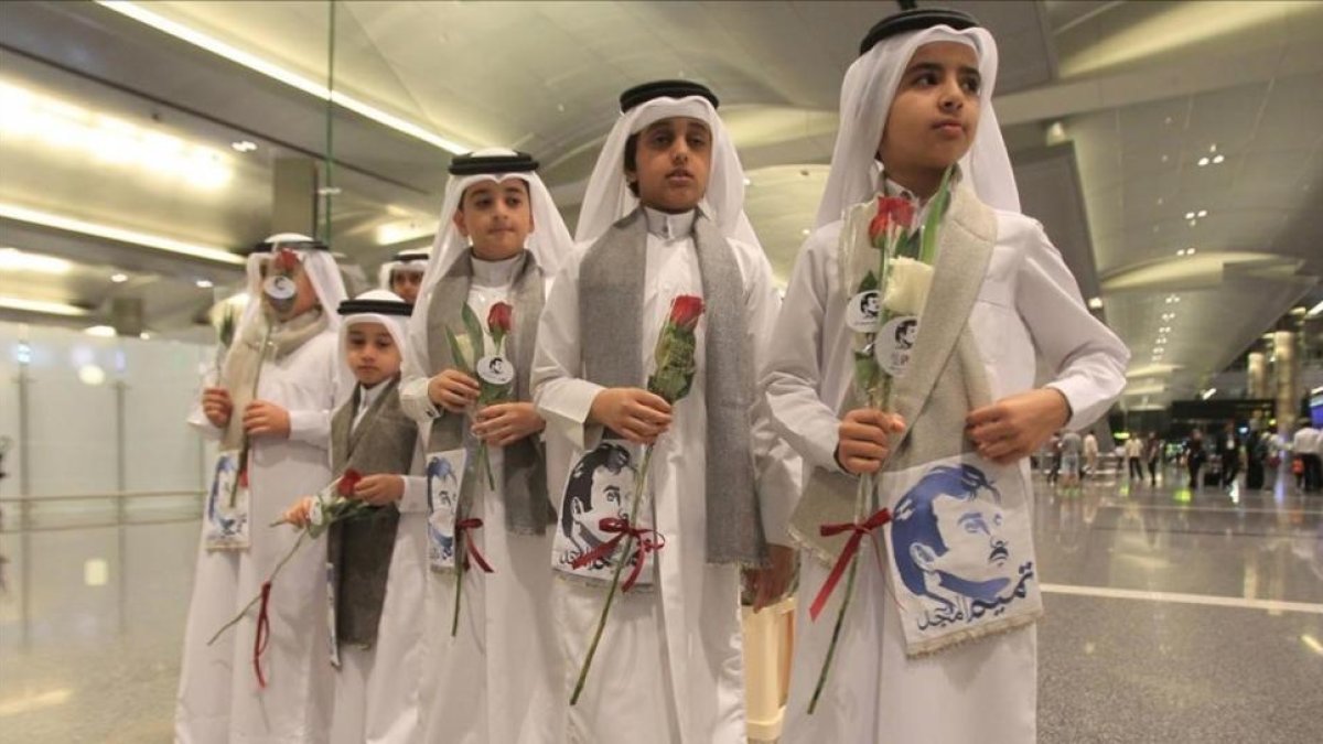 Niños qatarís con flores e imágenes del emir Al Thani reciben a ciudadanos de Kuwait y Omán, países que no se han sumado al boicot, en el aeropuerto de Doha.