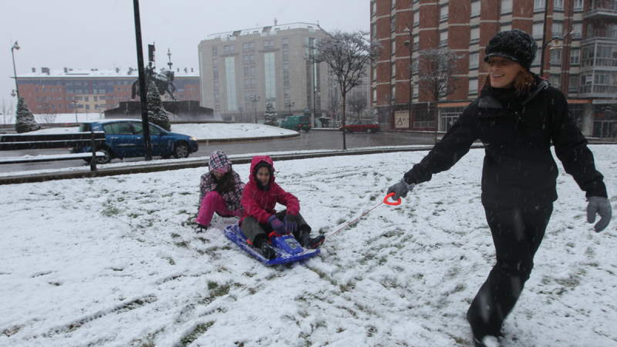 Dos niños juegan junto a su madre en uno de los parques del centro de Ponferrada.