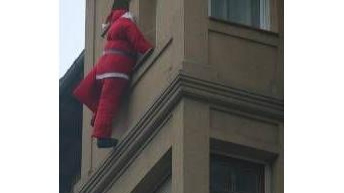 En la imagen, Papá Noél escala por uno de los edificios de la ciudad