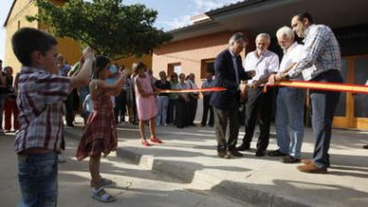 Dos niños fotografían a Álvarez, Llorente y Martínez cortando la cinta inaugural.