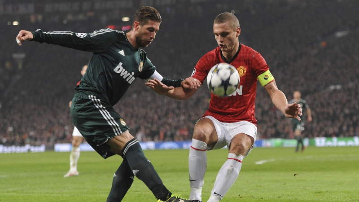 El defensa del Real Madrid, Sergio Ramos, disputa un balón con el fornido jugador serbio del Manchester United, Nemanja Vidic.