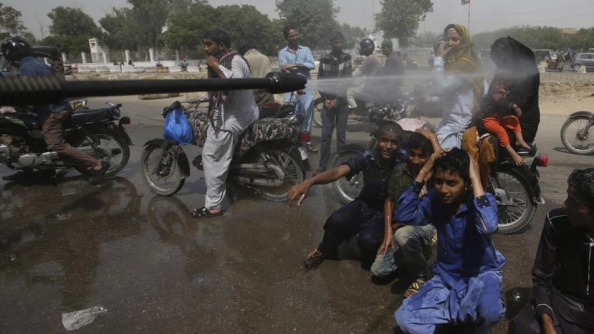 Voluntarios pulverizan a la gente en Karachi.