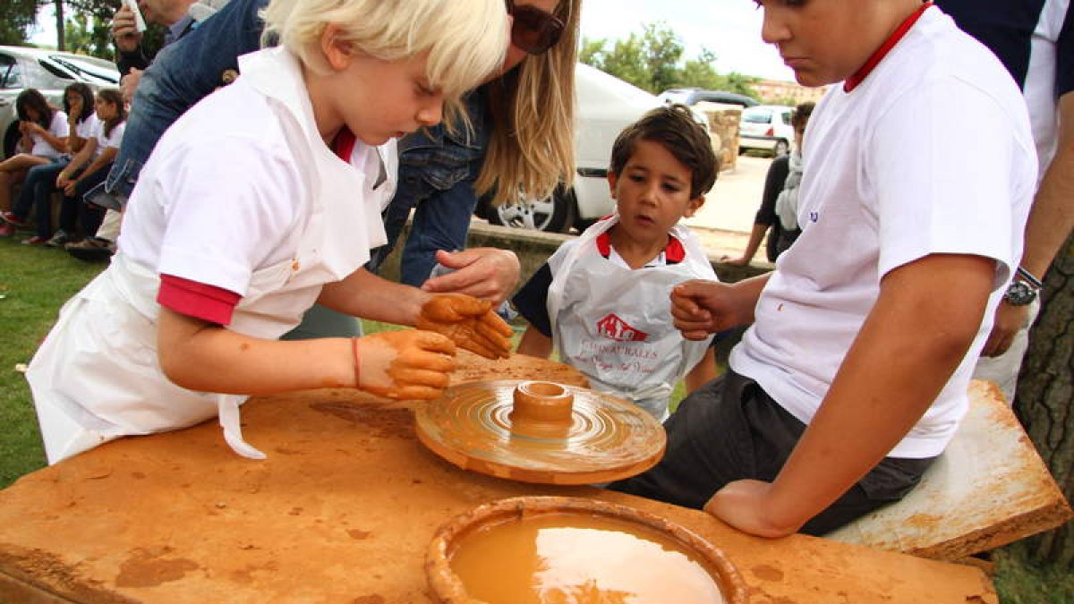 Niños en el taller infantil de alfarería de la feria de Val de San Lorenzo.