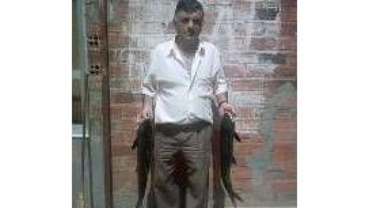 El pescador posa junto a su trofeo, dos barbos de casi tres kilos de peso