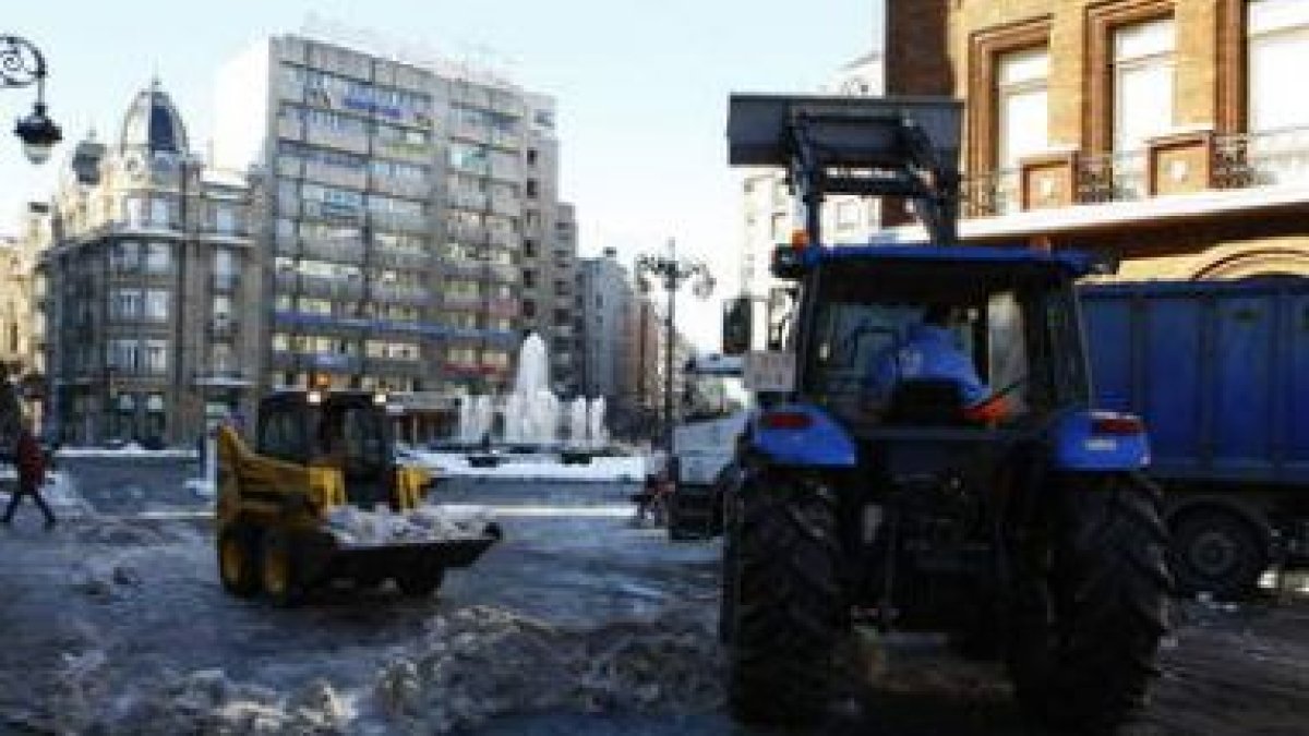 Operarios y maquinaria quitando ayer montones de nieve en el centro de la ciudad.
