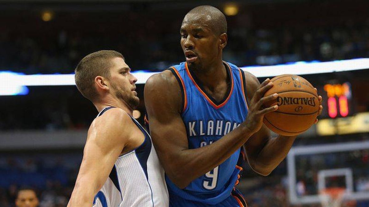 Serge Ibaka trata de deshacerse de Chandler Parsons, en el partido entre los Thunder y los Mavericks.