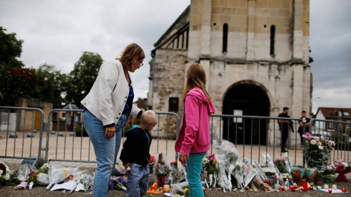 Una madre y sus hijos dejan flores ante la iglesia de Saint-Etienne-du-Rouvray.