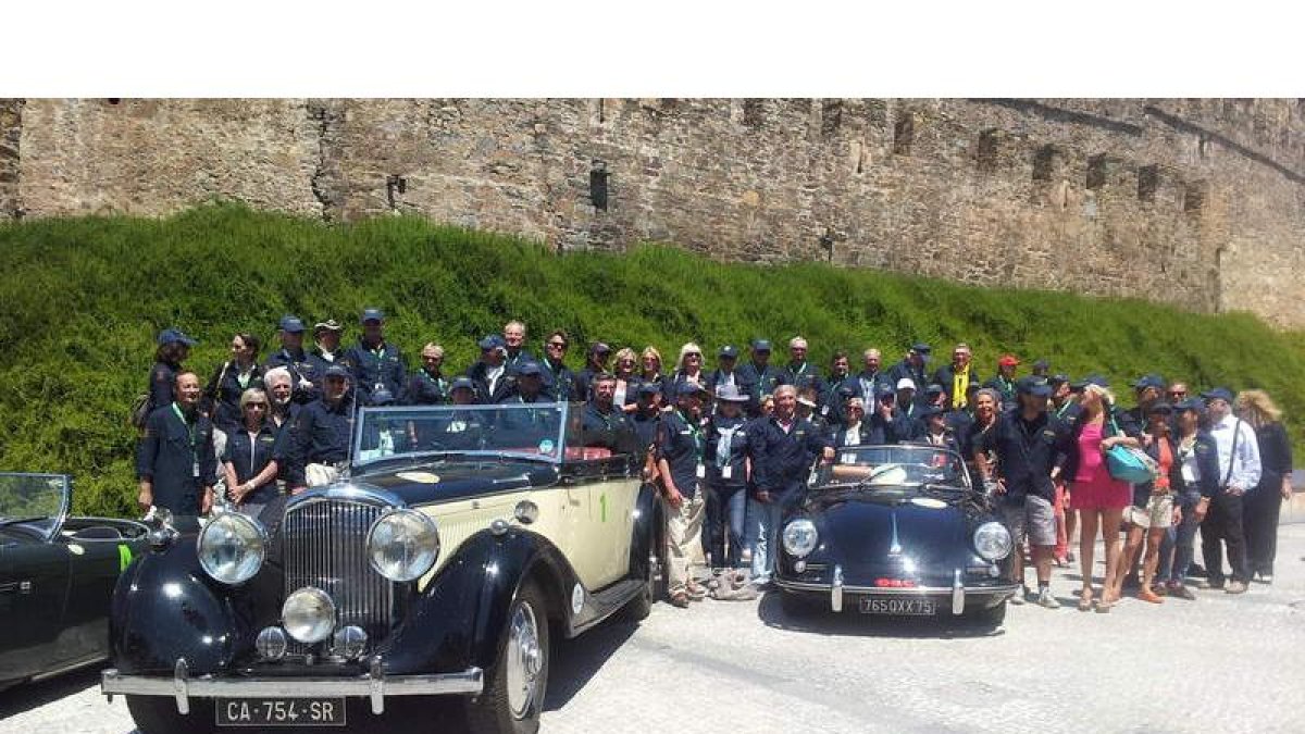 Los participantes en el rally galo con dos de sus coches, ayer frente al Castillo de los Templarios.