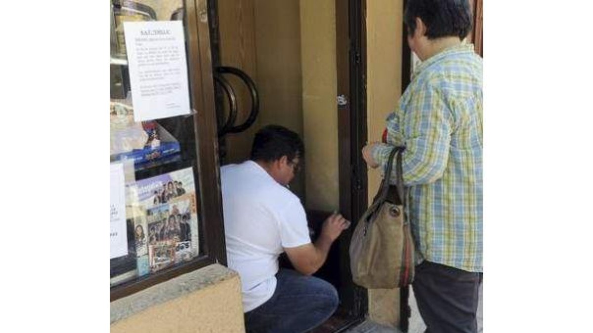 Un hombre limpia el estanco donde tuvo lugar el atraco.