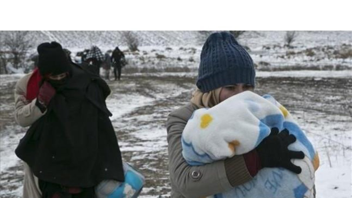 Una mujer migrante protege a su hijo con una manta mientras camina cerca de Miratovac (Serbia), este lunes.