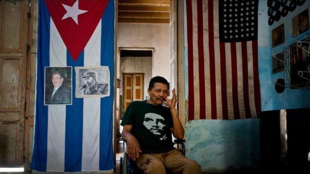 El cubano Armando Ricart Batista, actor y exboxeador, posa ante la bandera cubana y retratos de los Castro en su casa de la Habana.