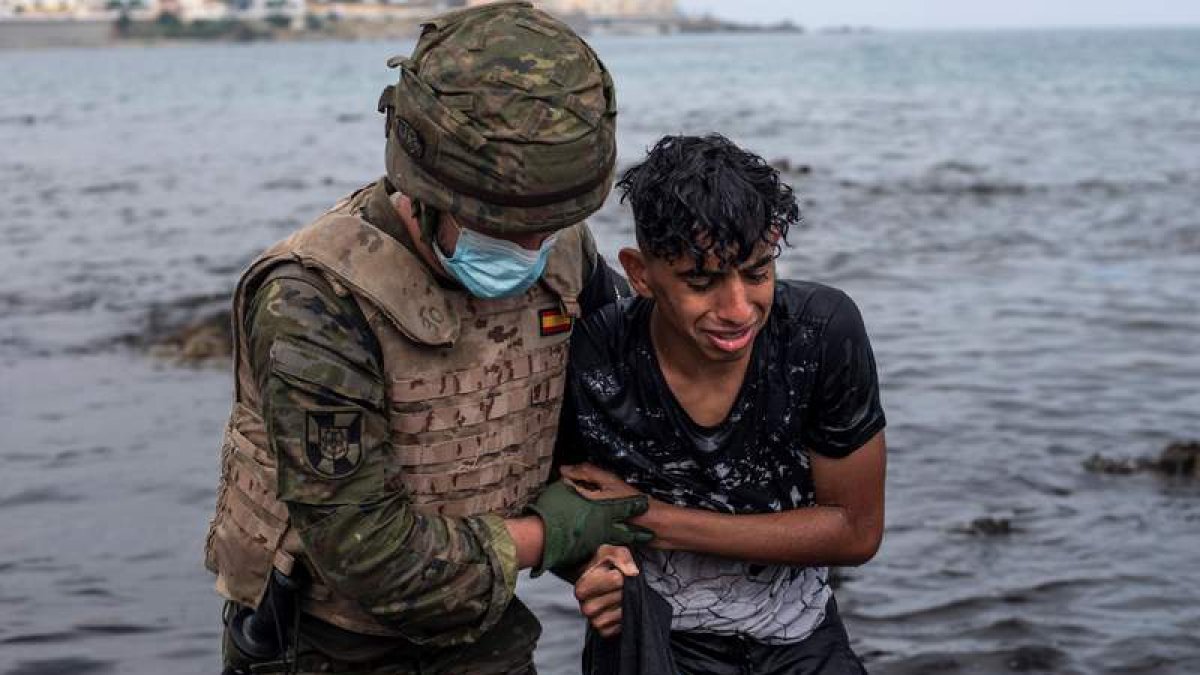 Un soldado del Ejército ayuda a un menor a salir del agua en la playa de El Tarajal. BRAIS LORENZO