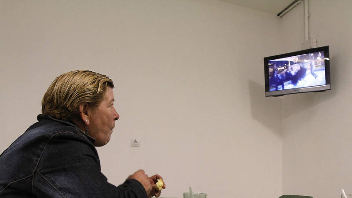 Una de las usuarias del centro de día toma un café mientras mira el televisor.