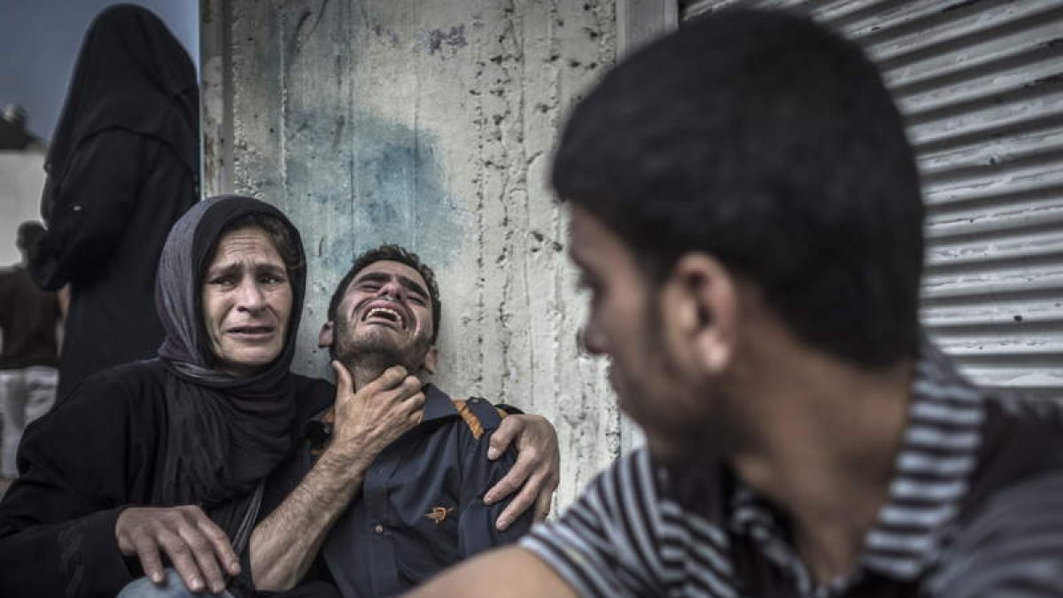 Varios palestinos lloran la muerte de sus familiares en el bombardeo a un colegio de la ONU.