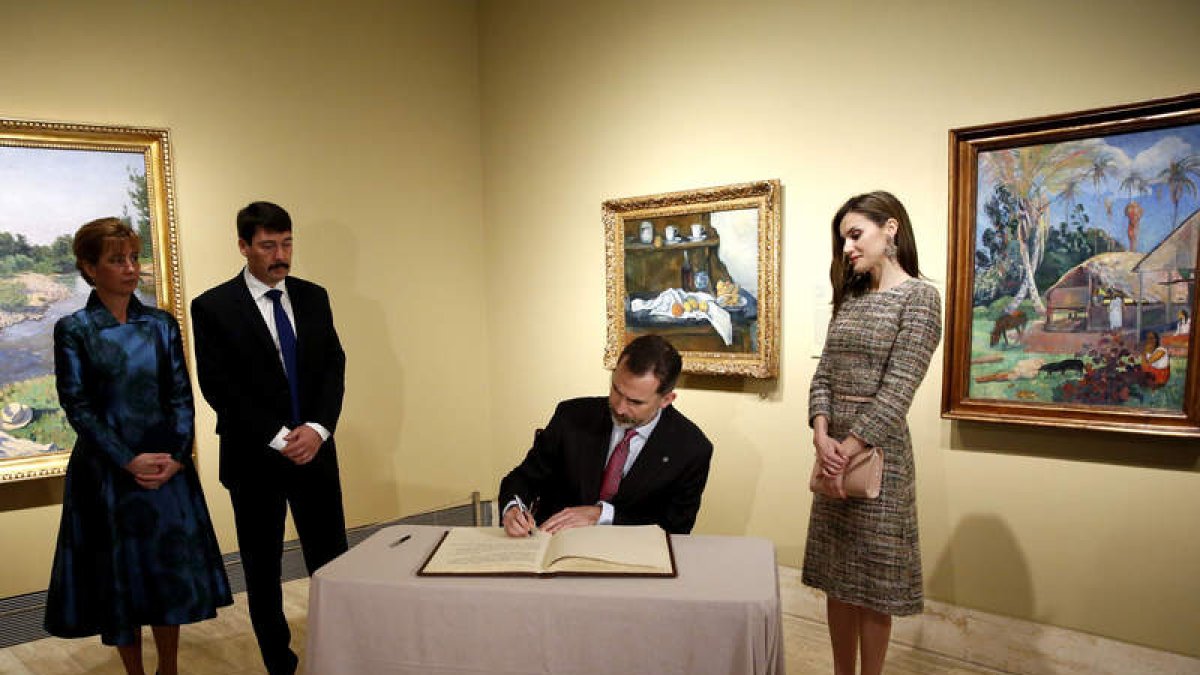 El rey firma en el libro de honor en presencia de su mujer y el presidente húngaro y su esposa. S. B.