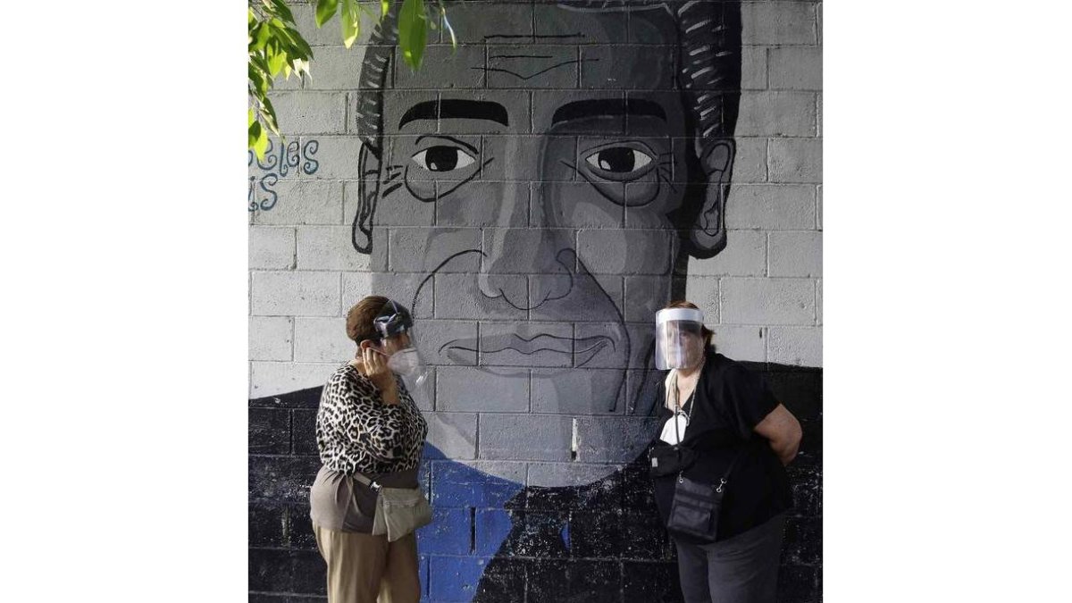 Dos mujeres conversan en la calle ante un graffiti. MIGUEL LEMUS
