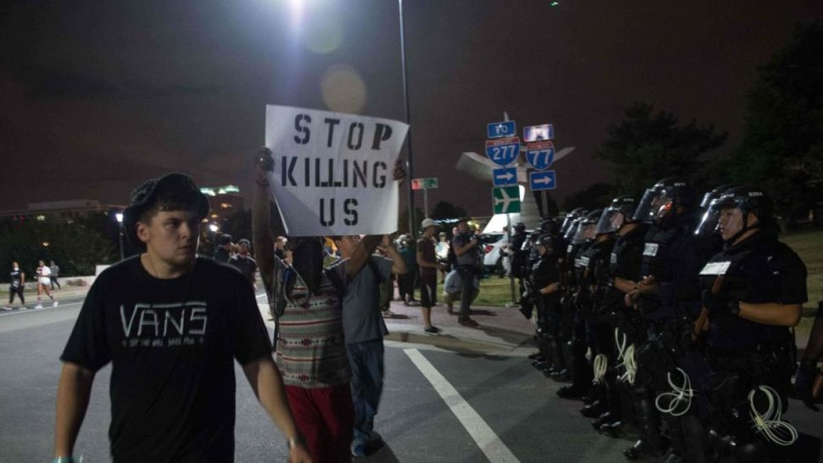 Manifestantes pasean con pancartas ante el cordón policial, esta madrugada en Charlotte.