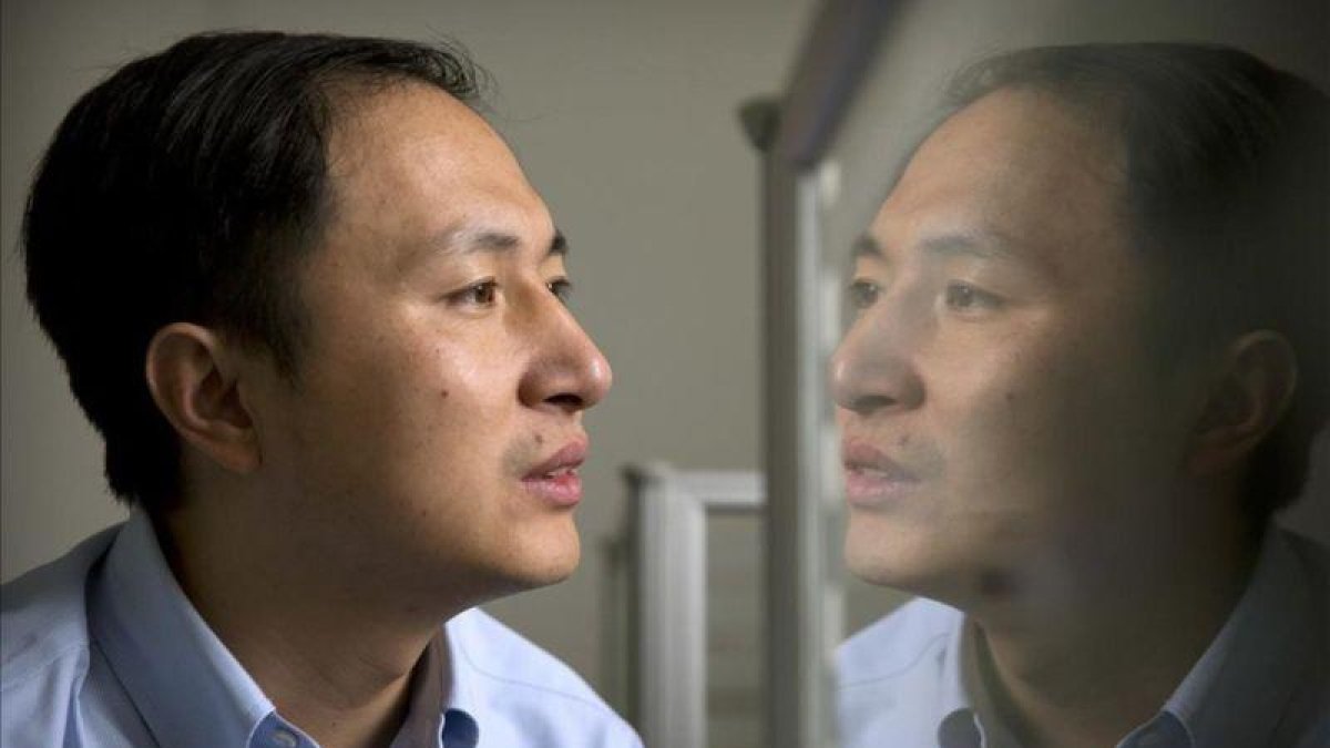 El doctor He Jiankui, reflejado en un panel mientras trabaja con el ordenador.
