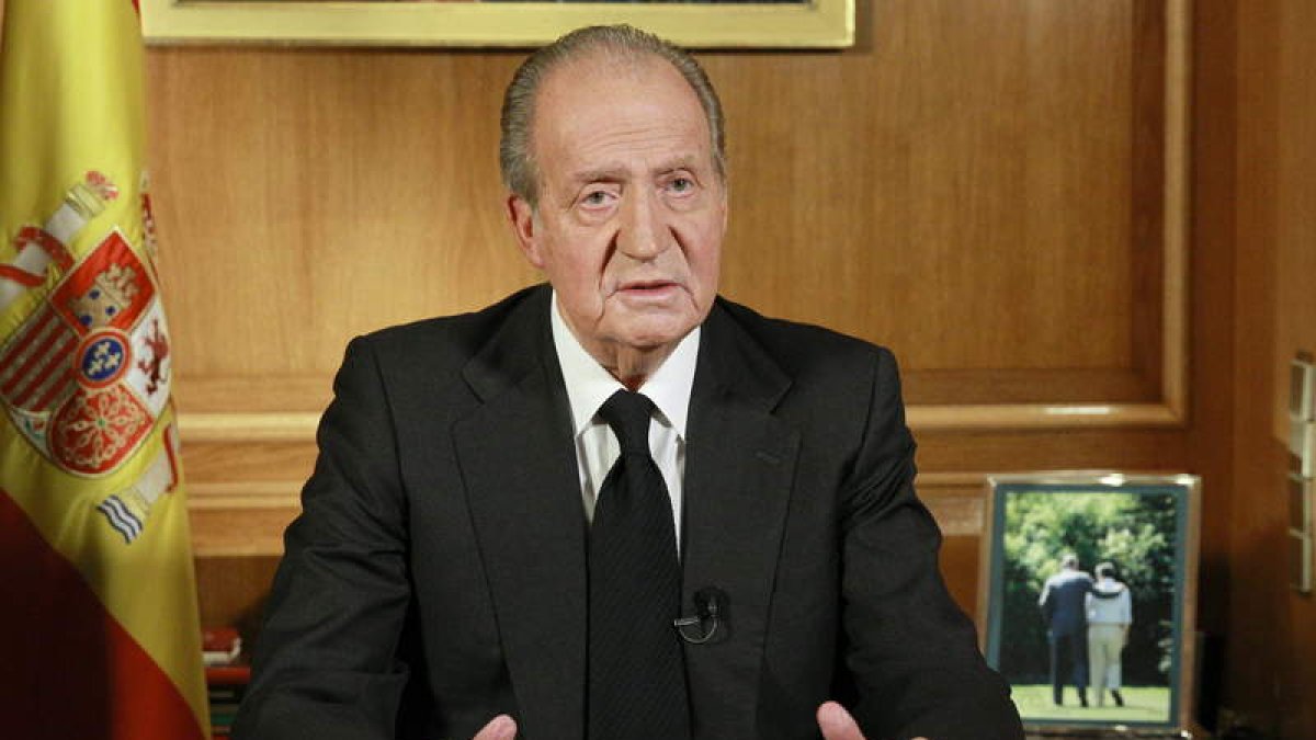 El rey, durante su mensaje de pésame, con la última fotografía que se hizo con Suárez, ambos de espaldas.