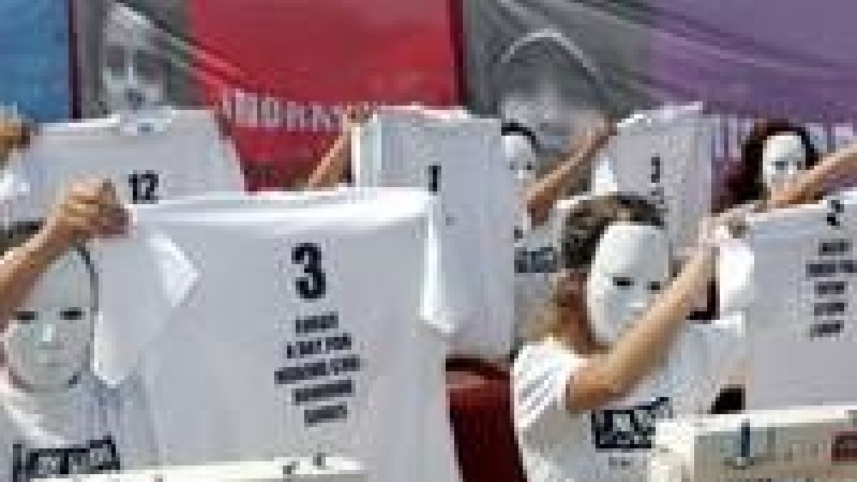 Caras tapadas con máscaras tras máquinas de coser en la protesta contra la explotación