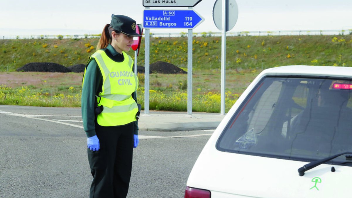 Un agente de la Policía Local de Ponferrada entrega una mascarilla a una vecina de la ciudad, después de haber atendido la petición de material de su marido. L. DE LA MATA