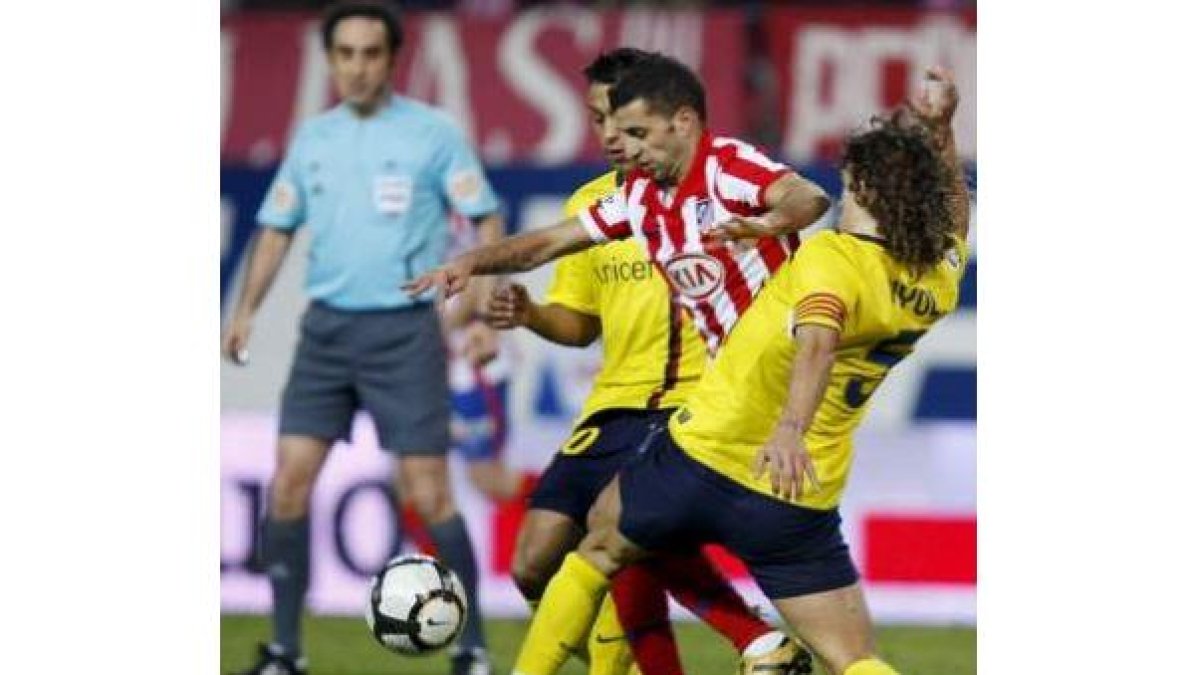 Simao Sabrosa trata de superar a dos jugadores del Barcelona, Jeffren y el capitán Puyol.