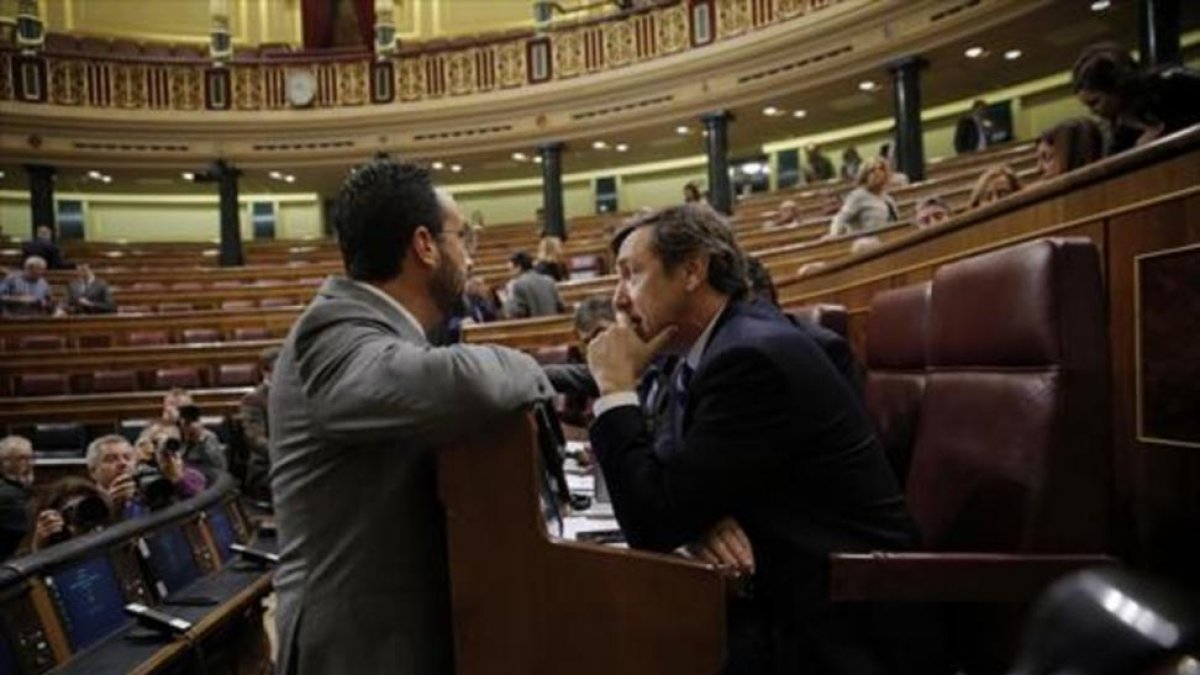 El socialista Antonio Hernando (izquierda) y el popular Rafael Hernando conversan en el hemiciclo del Congreso.