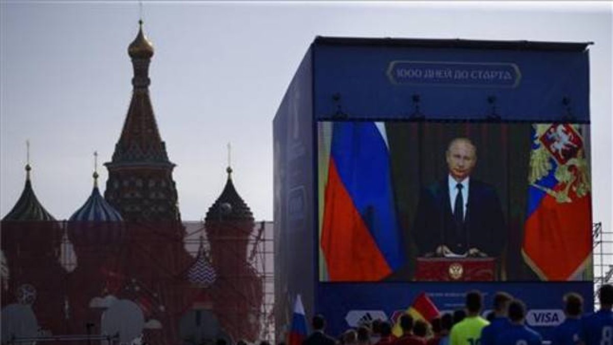 Un grupo de funcionarios y jugadores de fútbol miran el discurso televisado del presidente ruso, Vladimir Putin, en la Plaza Roja de Moscú, este viernes.