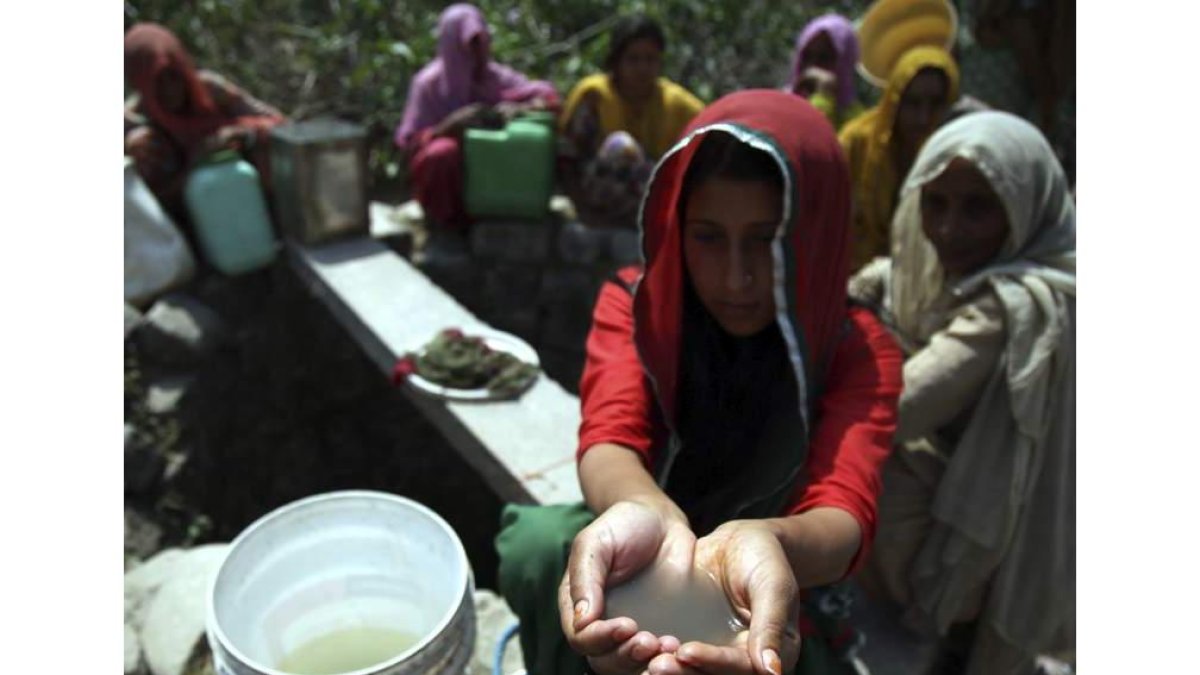 Una mujer muestra el agua sucia de un pozo de Padal. JAIPAL SINGH