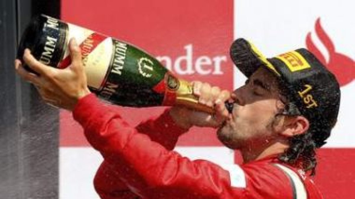 El piloto español de Fórmula 1 Fernando Alonso, de la escudería Ferrari, bebe champagne en el podio