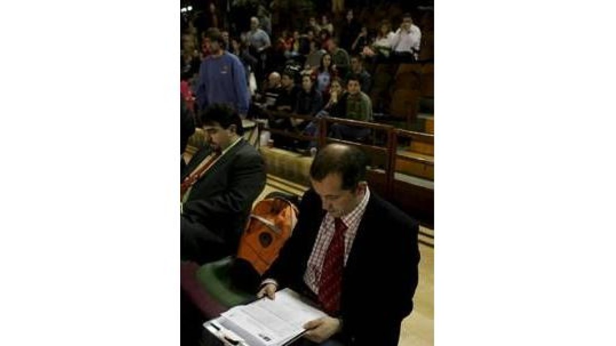 El técnico del Acis revisa sus notas durante un partido