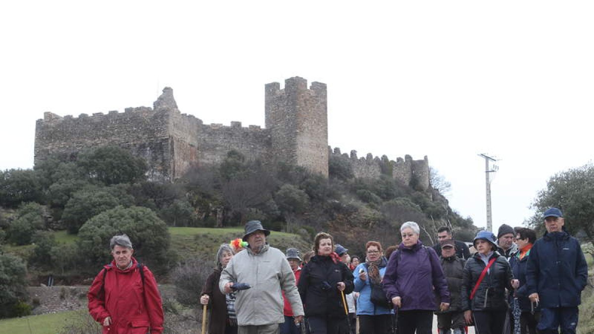 Caminantes por la ruta de invierno a Santiago dejando a sus espaldas el Castillo de Cornatel.